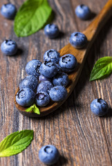 Fresh blueberries and mint leaf on wooden spoon