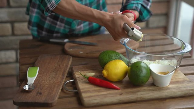 Woman squeeze the garlic for guacamole recipe in kitchen