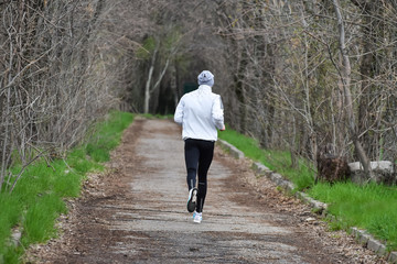 Guy jogging in a spring park