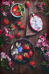 flatlay food background - empty wooden board with strawberries and pink flowers, copy space