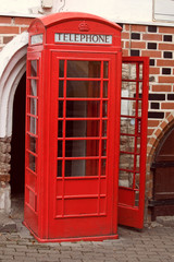 classic red English phone booth on the street, open door, no people