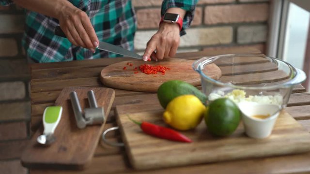 Woman cutting chili peper for guacamole recipe in kitchen 