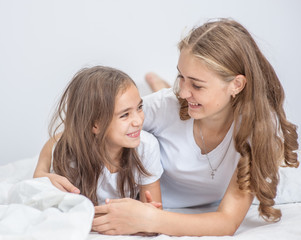 happy mother and daughter talking on the bed