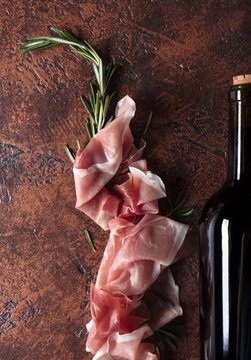 Prosciutto with rosemary and bottle of red wine.