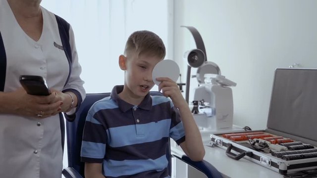 Little boy check his eyesight in oculist office