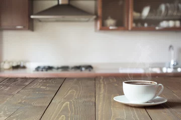 Rolgordijnen Cup of black coffee on wooden tabletop in blurred modern kitchen. Copy space. Indoor. © svetlana_cherruty