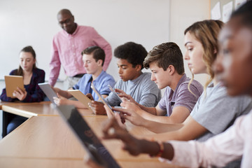 High School Teacher With Pupils Using Digital Tablets In Technology Class