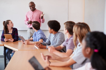 High School Teacher With Pupils Using Digital Tablets In Technology Class