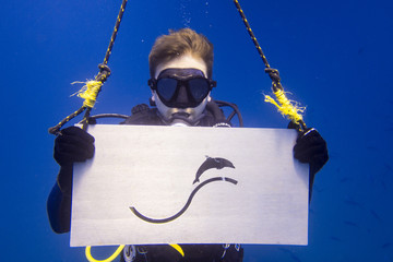 Taucher mit Ausrüstung Unterwasser im Meer guckt zum Betrachter