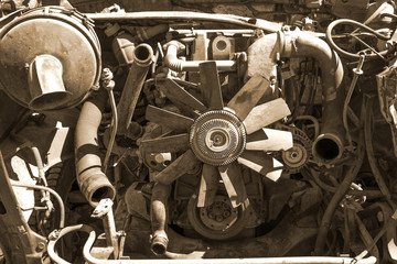 Old broken and dirty car engine close up, view under the hood in sepia tones