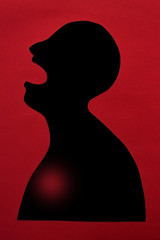 concept of human disease diagnosis and pain localization on silhouette - contour of abstract african man with opened mouth and heart failure, isolated on red background, top view, flat lay.