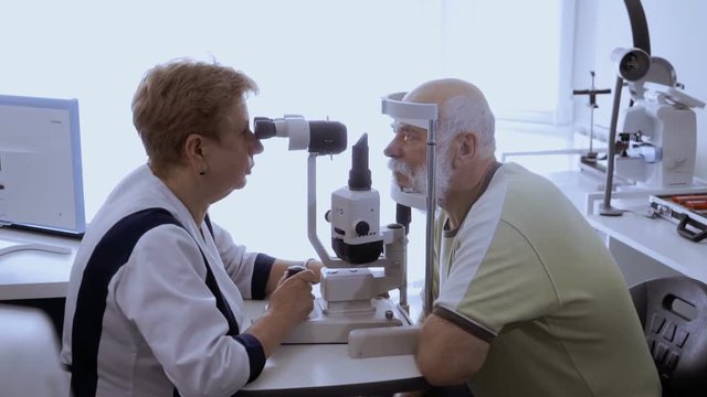 Oculist examing eyesight of senior man with biomicroscope