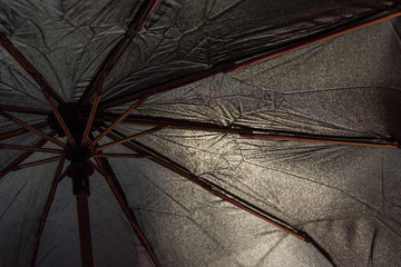 Black open umbrella underneath closeup. Rain protection.