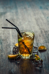 Delicious alcoholic cocktail with lemon and lime, pieces of ice on a wooden background