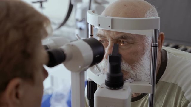 Ophthalmologist check eyesight of senior man with modern equipment