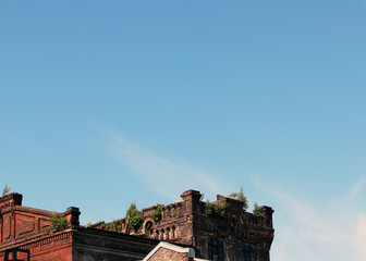 The roofs of old brick city buildings against blue sky and light cloud 