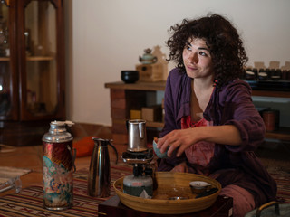 
Asian woman with curly hair prepares tea
