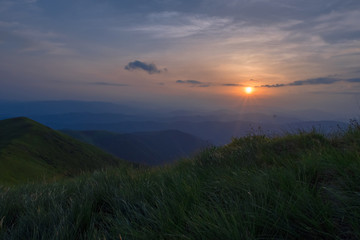 Sunrise in the mountains. Grass in the foreground.
