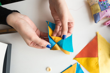workplace, handcraft, manufactoring concept. close up of delicate hands of seamstress, who is holding carefully pieces of fabric which she is going to stitch with each other