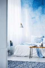 Patterned rug in modern, pastel blue bedroom interior with bed against ombre wall © Photographee.eu