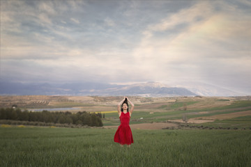 .Girl in red dress in the field at sunset