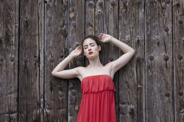 Fototapeta premium Portrait of a girl in red dress on a wooden door