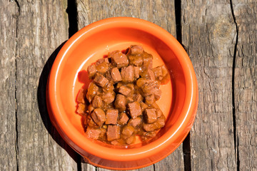 Canned food for cats or dogs in a orange plastic bowl