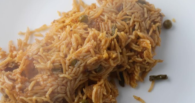 Close video of dumping steaming hot spicy rice onto a white plate.