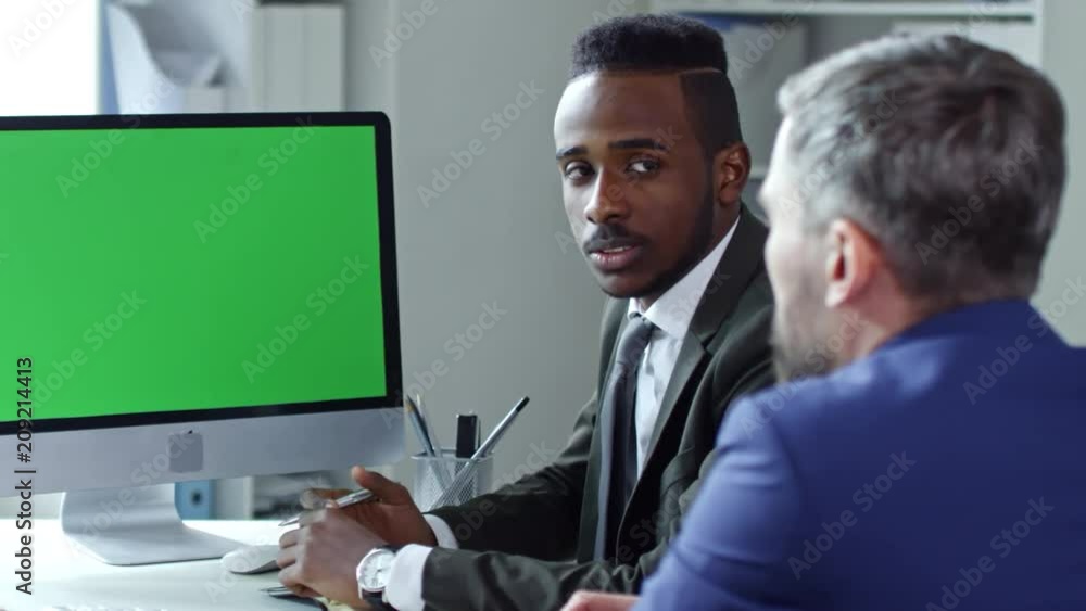 Poster multi-ethnic businessmen sitting at meeting table in the office and speaking via video call on compu