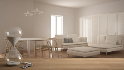 Wooden table, desk or shelf with hourglass measuring time in a countdown to a deadline, house keys over living room with sofa, architecture interior design, copy space background