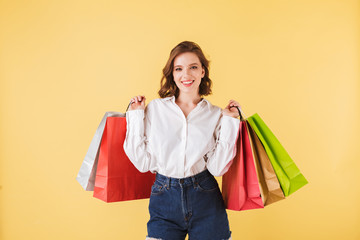 Portrait of beautiful smiling lady standing with colorful shopping bags in hands and joyfully...