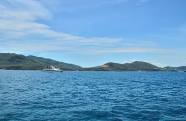 white walking catamaran in the sea, near the coastline of the island, against a background of sushi covered with greenery, the sky is covered with clouds, Nha Trang, Vietnam