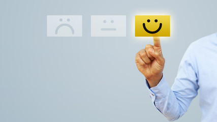 Hand of client show a feedback with smiley face card. Service rating, satisfaction concept