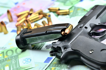 Close-up of handgun, loaded magazine and bullets on euro banknotes background