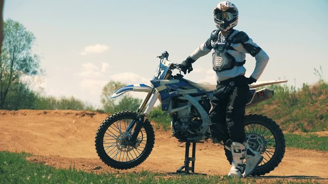 Equipped motorcycler is standing beside the autobike