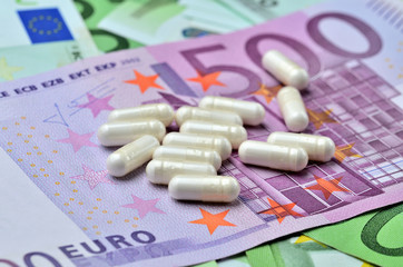 White capsule pills on euro banknotes - concept of healthcare and finance
