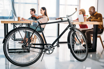 side view of bicycle and multicultural business people working in office