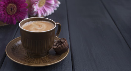 Delicious milk chocolate, a bouquet of fresh flowers and a morning aromatic coffee. Black wooden background, free space for text.