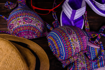 Swim suit, hat, sunglasses and flip flops on a wooden table. Top view. Summer vacation concept