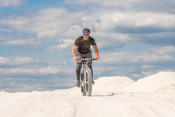Training a bicyclist in a chalky quarry. A brutal man on a fat bike.	