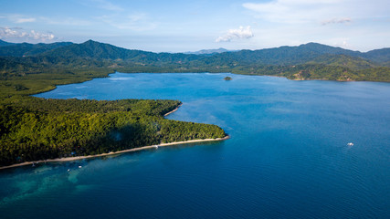 Obraz premium Aerial drone view of a beautiful tropical bay with reef, sandy beach and jungle scenery