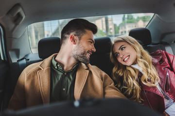 beautiful happy young couple smiling each other while sitting together in car