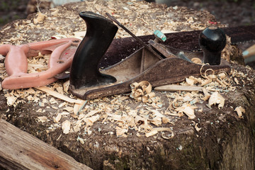 Tools carpenter - plane and saw in the sawdust on the stump, grunge effect