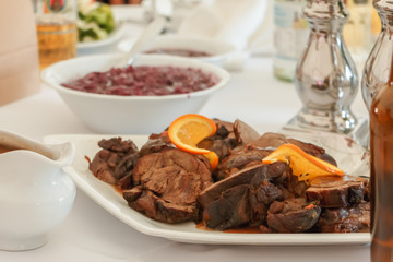 Gefüllte Schweinebraten mit Speckstreifen und Rotkohlsalat auf dem Tisch serviert.