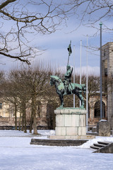 Fototapeta premium Germany, Bavaria, Munich, Hofgarten: Winter scene of War memorial with equestrian statue, white snow, public park in famous Court Garden in the German city center of the Bavarian capital and blue sky.