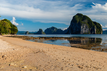 Offshore islands reflected in a flat calm ocean from a tropical beach