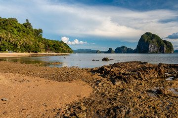 A beautiful tropical beach with large limestone karsts out to sea (Las Cabanas Beach, Palawan)