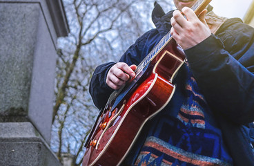 Street musician busker playing jazz guitar in urban city environment.