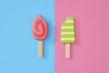 Ice cream popsicles lollipops on blue and pink pastel background for summer.  Wooden ice cream lollies toys