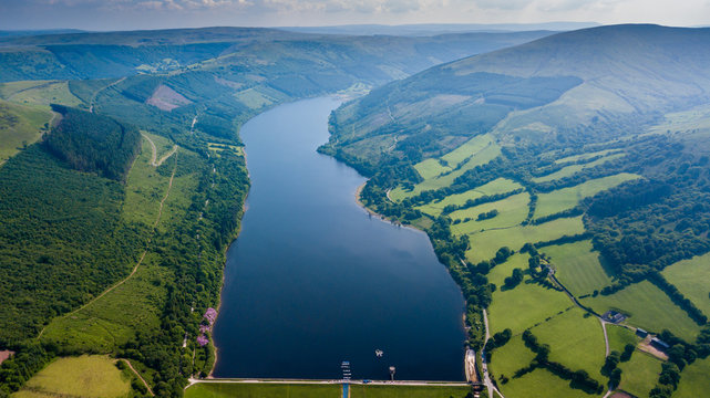 Aerial view of a large reservoir in a deep valley surrounded by green fields (Tal-y-Bont, Wales)